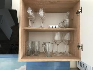 a shelf with wine glasses and other glass items at Familienapartment am Strand in Primorsko in Primorsko