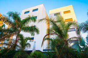 Apartamentos 16:9 Suites Almería في ألميريا: مبنى ابيض امامه اشجار النخيل