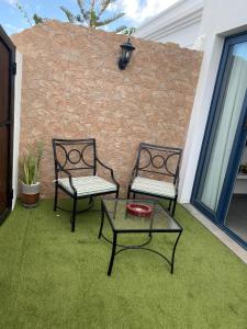 2 Stühle und ein Tisch auf einem Hof mit Ziegelwand in der Unterkunft Rosales in Playa Blanca