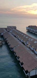 una fila de muelles en el agua al atardecer en Water Chalet or Premium Tower Seaview Port Dickson , Private Room en Port Dickson