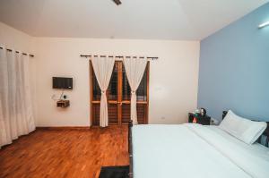 um quarto com uma cama branca e piso em madeira em Hidden Heaven em Coonoor