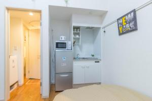 a small kitchen with a refrigerator and a microwave at japan house Ikebukuro in Tokyo