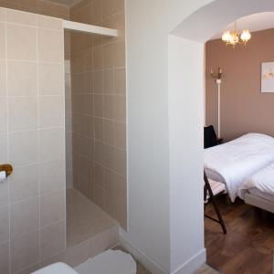 a bathroom with a walk in shower next to a bed at Entre Nous in Rozoy-sur-Serre