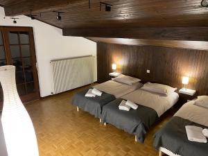 a bedroom with two beds and a wooden wall at CHALET DE MANU in Sondernach