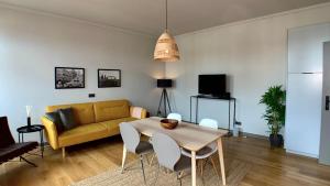 a living room with a table and a yellow couch at cosy and modern in vibrant west leipzig in Leipzig