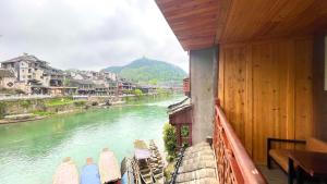 a view of a river from a balcony with chairs at Bian Cheng Xing Zi Inn in Fenghuang County