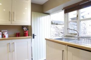 eine Küche mit weißen Schränken und einer Spüle und einem Fenster in der Unterkunft St Antony's Cottage in Stow on the Wold + 15 Fotos