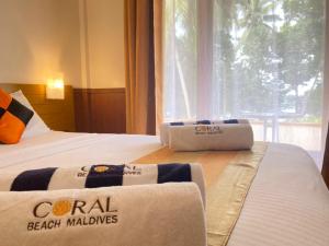 a hotel room with two beds with towels on them at Coral Beach Maldives in Hangnaameedhoo