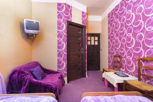 a purple room with a chair and a tv at Dom Gościnny Przedmieście in Kielce