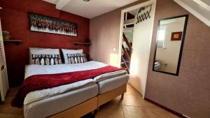 ein Schlafzimmer mit einem Bett mit einer roten Wand in der Unterkunft Belle-Swan in Simpelveld