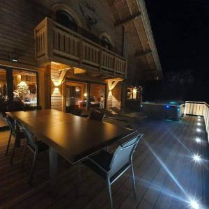 drewniany stół i krzesła na tarasie w nocy w obiekcie Nouveau Chalet M.META 12 pers sauna,jacuzzi,billard w mieście Xonrupt-Longemer