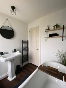 a white bathroom with a sink and a mirror at Aintree Lodge - Hot Tub - Northumberland in Swarland