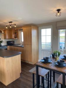 a kitchen with wooden cabinets and a table with chairs at Aintree Lodge - Hot Tub - Northumberland in Swarland