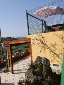 um pátio com uma mesa, um guarda-chuva e uma pedra em Varandas da Serra II em Vila Franca de Xira