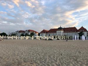 a building on the beach with chairs in the sand at Apartament Gold 300 m do Plaży - Praia Apartments Sopot in Sopot
