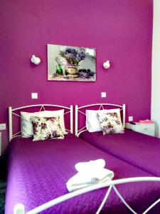 two beds in a room with purple walls at Nancy Rooms in Skala Kallonis