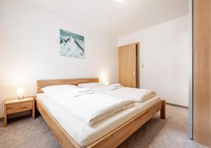 een slaapkamer met een groot bed met witte lakens bij Appartement Marlenka in Umhausen