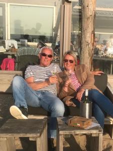 un uomo e una donna seduti su un divano con bicchieri da vino di Bed and Breakfast Kik en Bun a Katwijk aan Zee