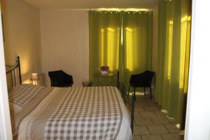 a bedroom with a bed with green curtains and chairs at Chambres d'hôtes La Prairie in Belley