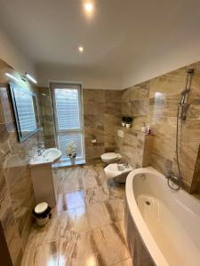 a bathroom with a tub and a toilet and a sink at Penzion Vegas in Partizánske