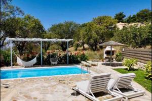 een zwembad met 2 ligstoelen en een hangmat bij Sea Breeze Apartments - n.1 with private pool in Kalamitsi