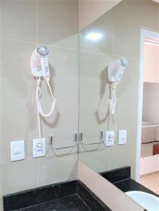 um chuveiro com dois telefones na parede de uma casa de banho em Hotel Bellavista em Paulo Afonso