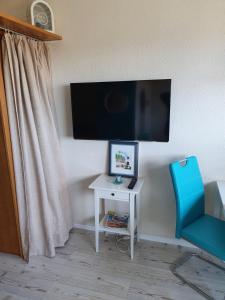 um quarto com uma televisão, uma mesa e uma cadeira em Kleine Hafenliebe em Fehmarn