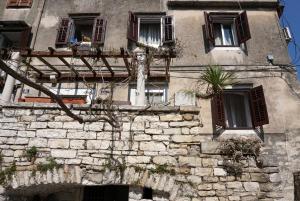an old stone building with windows and a plant at Mućo Varoš in Split