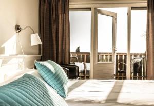 Schlafzimmer mit einem Bett und Blick auf einen Balkon in der Unterkunft Loods Hotel Vlieland in Oost-Vlieland