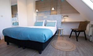 
a bedroom with a bed and a chair at Loods Hotel Vlieland in Oost-Vlieland
