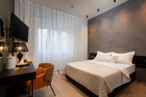 een slaapkamer met een bed, een bureau en een televisie bij Aborda Rooms in Split