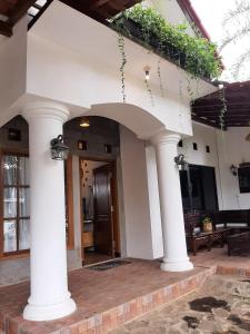 una casa con colonne e un portico con porta di OMAH LUMUT Malang, Best Family Villa 3 Bedrooms Free Pool Kolam Renang a Malang