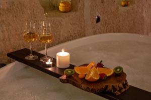 a candle and two glasses of wine and fruit in a bath tub at Sato Cave Hotel in Göreme