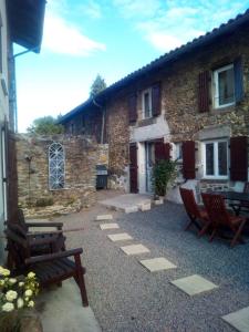 a stone house with two chairs and a patio at Le Jolie Grenier a Foin in Saulgond