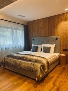 sypialnia z dużym łóżkiem i drewnianą ścianą w obiekcie Florisa Mountain Penthouse w mieście San Vigilio di Marebbe