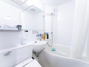 La salle de bains blanche est pourvue d'un lavabo et d'une douche. dans l'établissement APA Hotel Ginza-Takaracho Tokyo Yaesu Minami-guchi, à Tokyo
