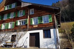 a wooden house with green shuttered windows and a door at Bauernhaus mit Charme, Traumaussicht und Sauna in Weggis