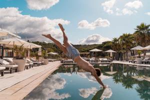 a man diving into a swimming pool at a resort at Marina di Scarlino Resort in Puntone di Scarlino