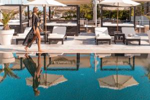 a woman walking past a pool of water at Marina di Scarlino Resort in Puntone di Scarlino