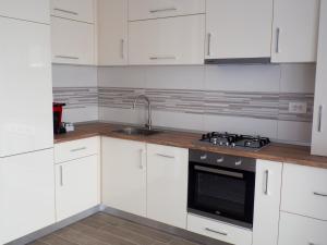 a kitchen with white cabinets and a sink and a stove at Armony Apartament Timisoara in Timişoara