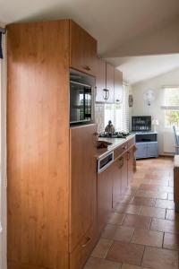 a large kitchen with wooden cabinets and a tile floor at Groot Marquette - Noord Holland aan uw voeten in Warmenhuizen