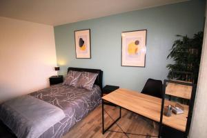 サルグミーヌにあるAppartement tout confort, meublé et équipé.のベッドと木製のテーブルのある寝室