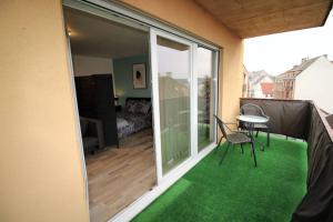 サルグミーヌにあるAppartement tout confort, meublé et équipé.のバルコニー(緑の床、テーブル、椅子付)