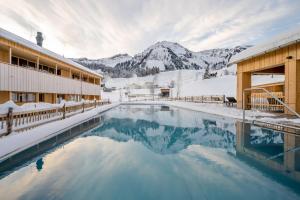 uma piscina de resort com montanhas cobertas de neve ao fundo em Fuchsegg Eco Lodge em Egg