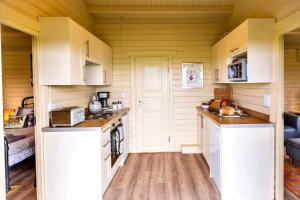 a small kitchen with white cabinets and wooden floors at The Retreat Log Cabin in Sudbury