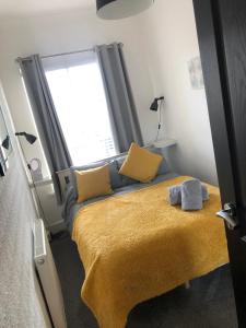 a bedroom with a bed with yellow pillows and a window at City Centre Victorian Terrace in Cardiff