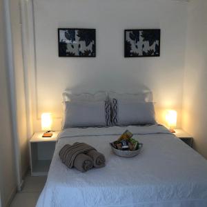 a white bed with a basket of towels and two lamps at Toca da Villa in Fernando de Noronha