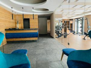 a fitness room with blue chairs and a gym at Ciampedie Luxury Alpine Spa Hotel in Vigo di Fassa