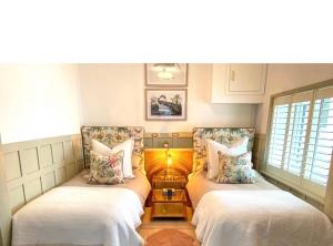 2 camas en una habitación con 2 ventanas en Cotswolds Lodge in Minster Lovell, en Minster Lovell