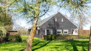 a house with a black roof on a green yard at d'Ouwe stal in Axel